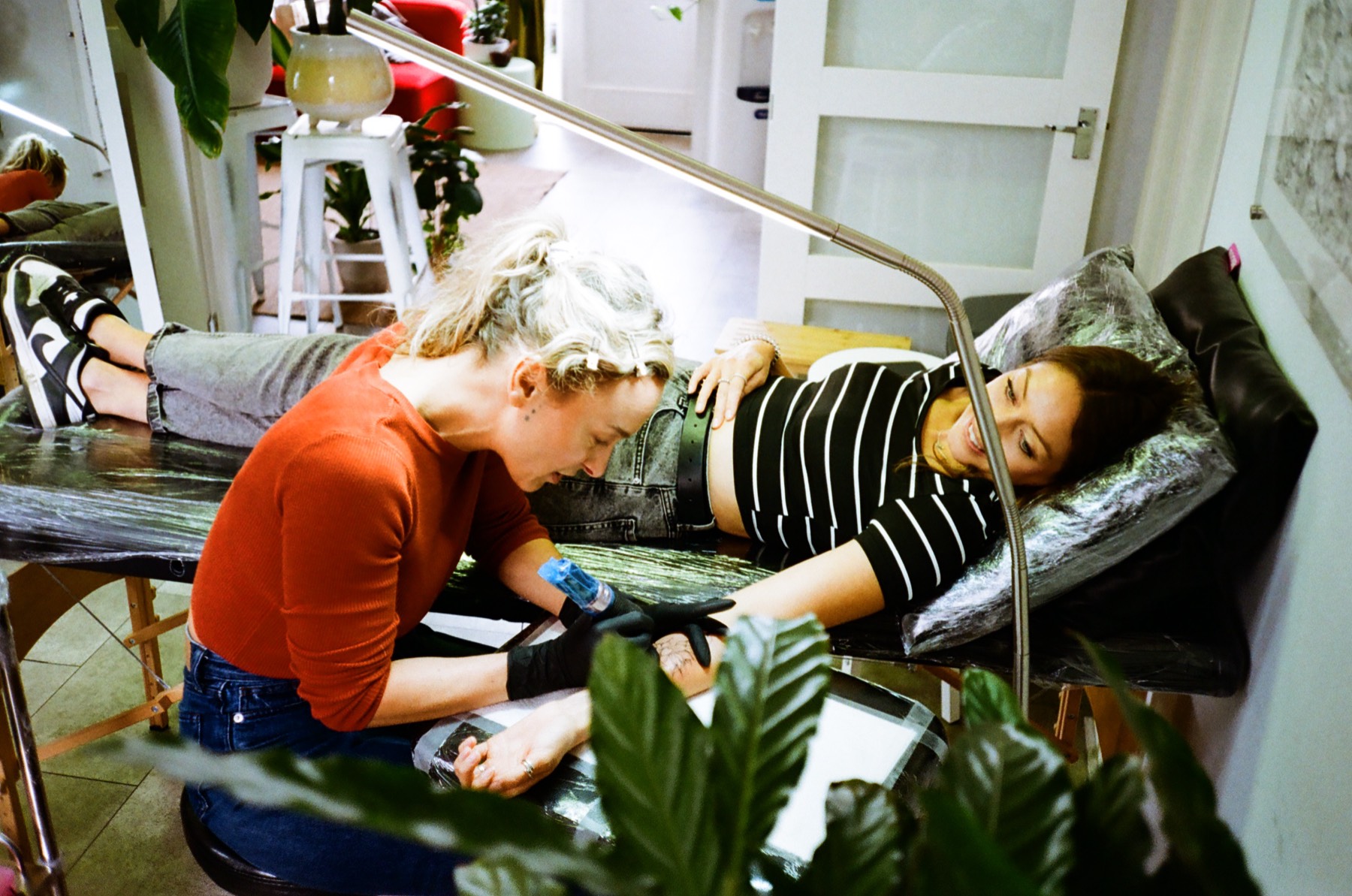Gosia tattooing a reclining client in her plant-filled Bristol studio